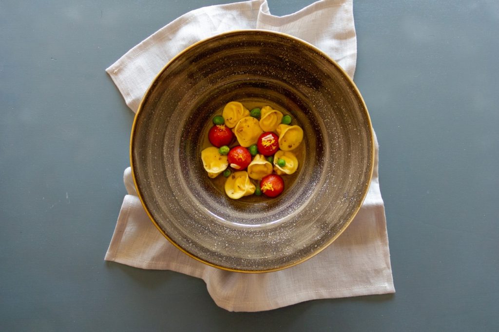 Tortelli ripieni di ricotta di pecora, pomodori canditi, piselli
