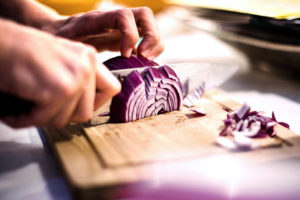 Frutta e verdura viola e blu mani che tagliano cipolla