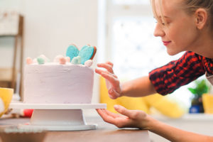 Ricette-con-Valle-Pasticceria-ragazza-donna-bionda-che-decora-torta-rosa-e-lilla-camicia-a-righe-rossa-e-nera